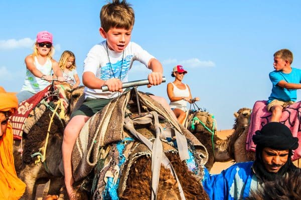 Children riding camels with local guides in the Moroccan Sahara Desert