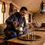 Berber host pours tea at desert camp